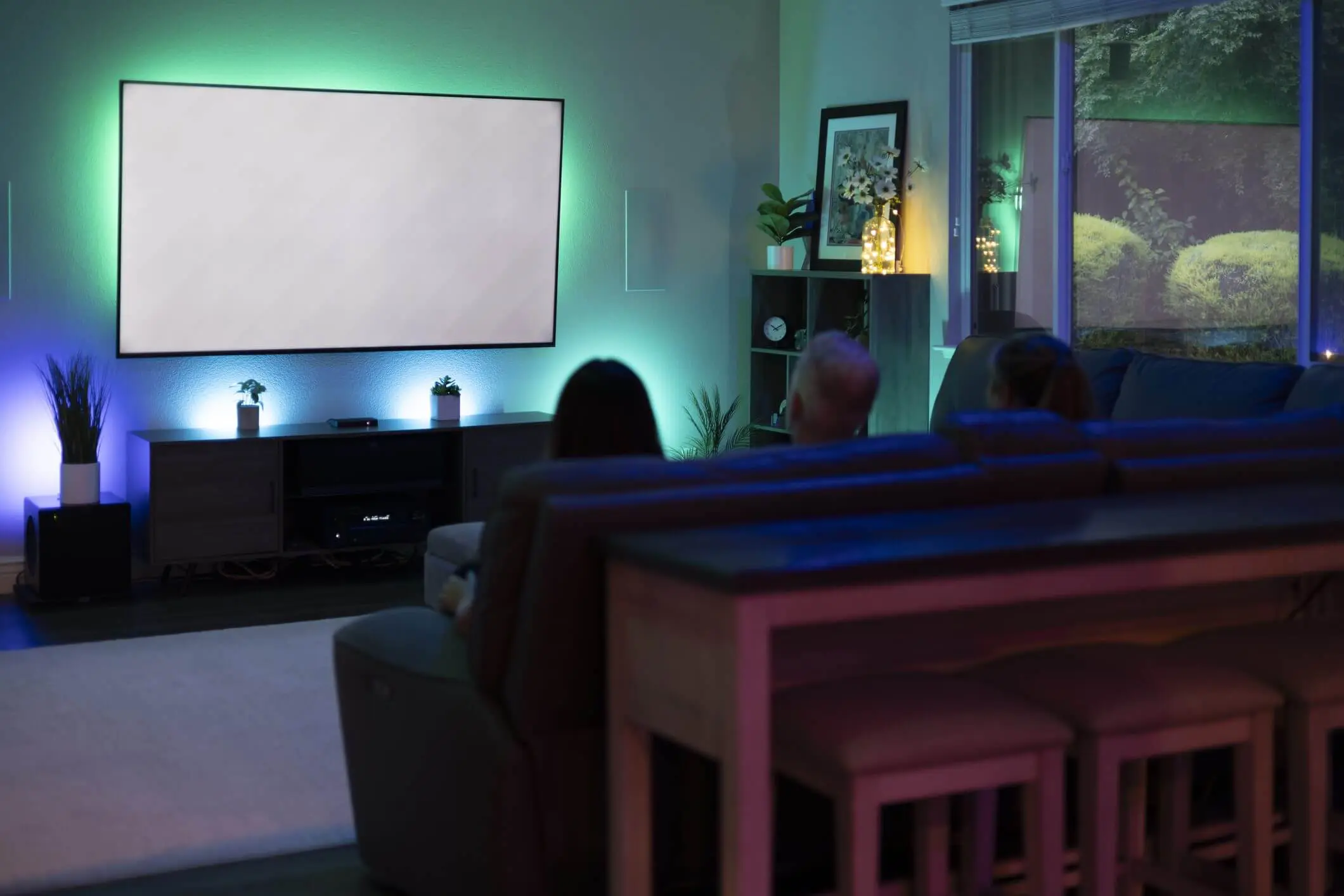 Cozy home theater with ambient lighting and people watching a movie.