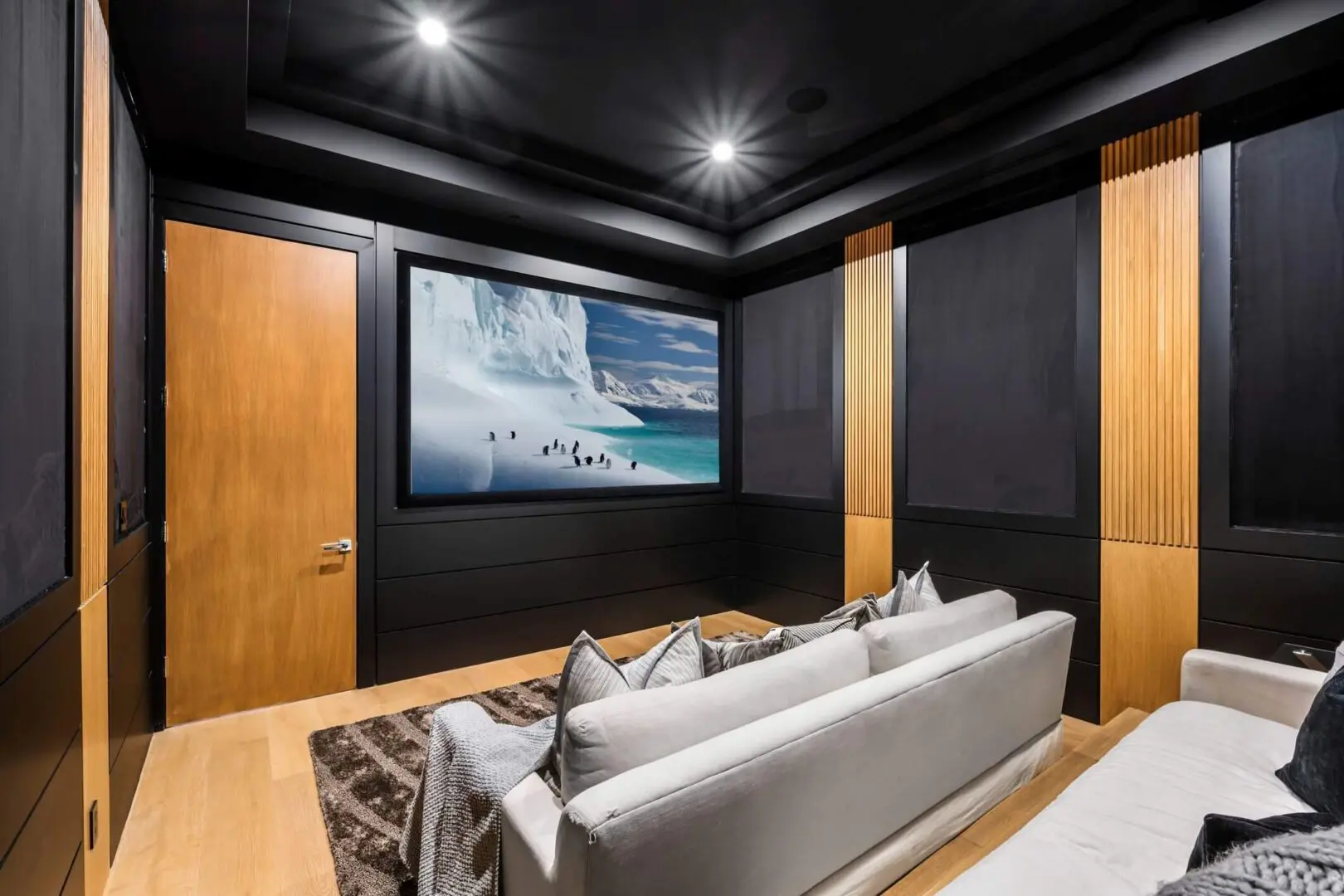 Modern home theater room with large screen and cozy seating.
