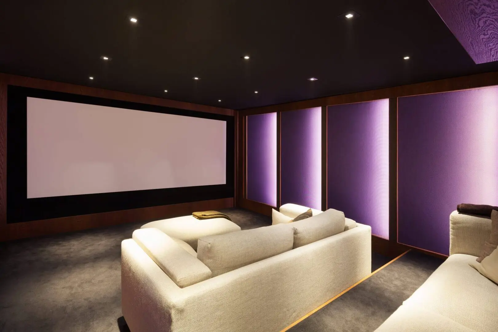 Modern home theater with cozy seating and ambient purple lighting.