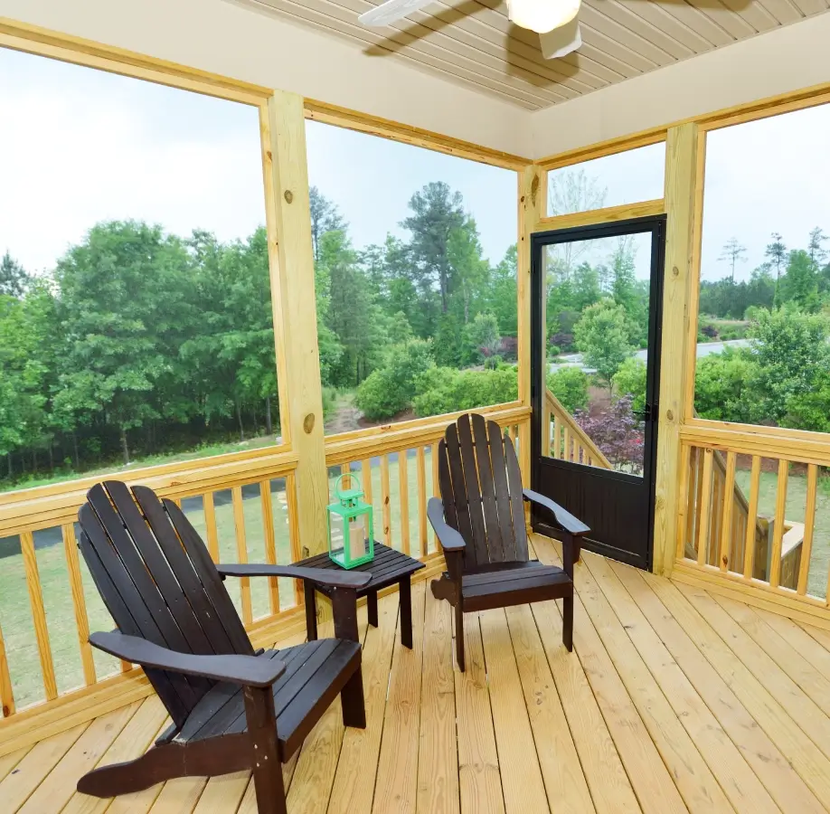 Screened porch with Adirondack chairs and table.