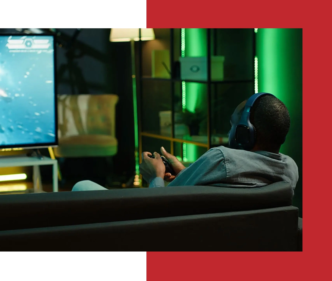 Person gaming on couch with headphones on.
